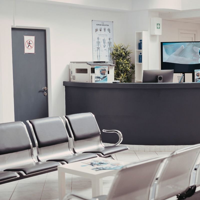 Medical office space with grey chairs and a large desk.