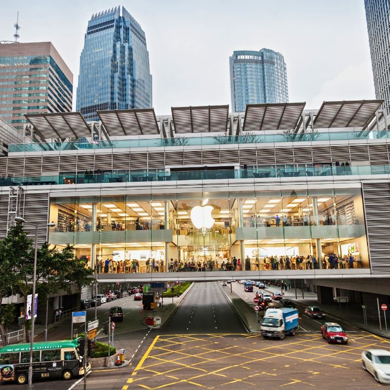 Apple store with large glass windows and skyscrapers behind it.